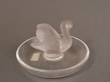 a glass swan sitting on top of a glass plate