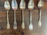 six cuillères en argent alignées sur une table en bois
