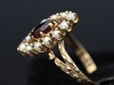 a close up of a gold ring with pearls and garnets