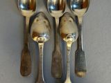 four silver spoons and two silver spoons on a gray surface