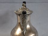 a silver vase with a black top sitting on a table