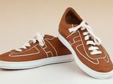 une paire de baskets marron avec des lacets blancs sur fond beige