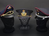 three military hats on a mannequin head on a black background