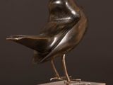 statue of a bird on a marble base on a wooden table
