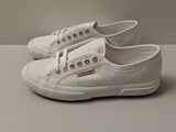 white canvas sneakers with laces on the side of them on a white surface