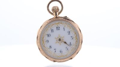 une montre de poche en or avec un cadran blanc sur une surface blanche