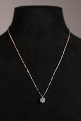 a woman wearing a necklace with a diamond pendant on it