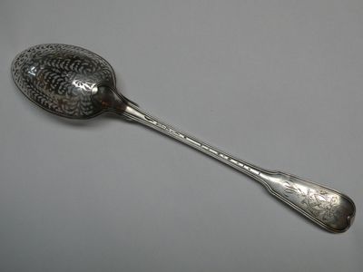 silver plated spoon with a pattern on it on a gray surface