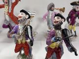 five figurines of men dressed in different costumes