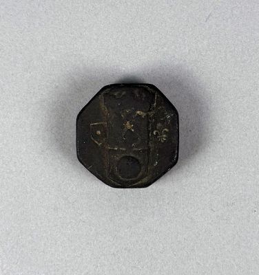 an old coin with a face on it sitting on a white surface