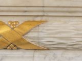 a close up of a gold cross on a marble wall