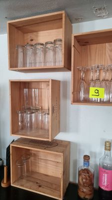 Plusieurs verres à vin vides sont empilés sur une étagère en bois
