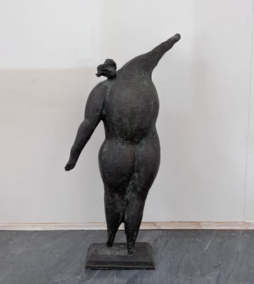 sculpture représentant une femme debout sur un socle, de dos par rapport à la caméra