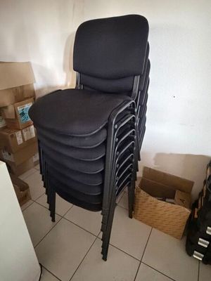 une pile de chaises noires dans un coin de la pièce