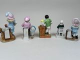five figurines of children sitting on a bench