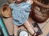 a doll that is sitting on a table next to a clock