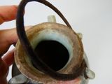 une personne tenant un petit vase muni d'une anse marron