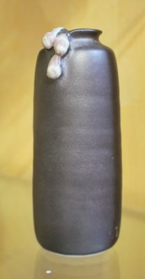 un vase noir orné d'une fleur, posé sur une table en verre
