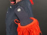 navy blue coat with red fringes and a black hat on a mannequin