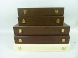 three brown suitcases stacked on top of each other on a white surface