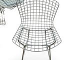 the chair is made of wire and has a cushion on top of it