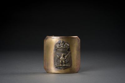 an old brass cup with a crest on it