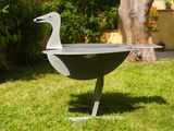 a bird that is sitting on a grill in the grass