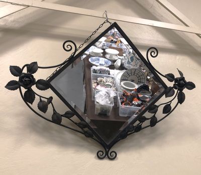 a mirror hanging on the wall with a bunch of dishes