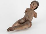 an old wooden figurine of a baby laying on the ground
