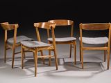 three wooden chairs with grey cushions sit in a dark room