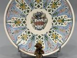une image représentant une assiette décorative sur laquelle se trouve une statuette posée sur un socle