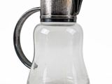 a glass pitcher with a metal lid on a white background