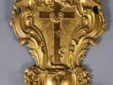 a gold clock hanging on the wall with a cross on it