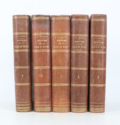 six vieux livres sont alignés sur une surface blanche