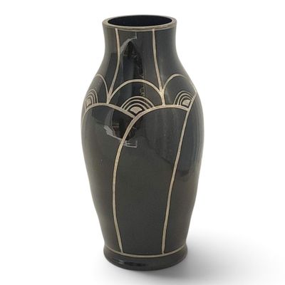 a black vase with a design on it on a white surface
