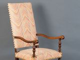 une vieille chaise en bois dont l'assise est recouverte d'un tissu à motifs
