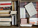 many books in a box that are stacked together