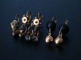 two pairs of earrings are sitting on a blue surface
