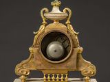 a gold clock on a marble base with a vase on top