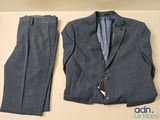 un costume et une cravate posés sur une table à côté d'un pantalon