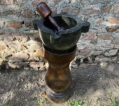 un mortier et un pilon posés par terre près d'un mur de briques