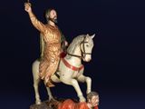 statue of a man on a horse with a sword and a man laying on the ground