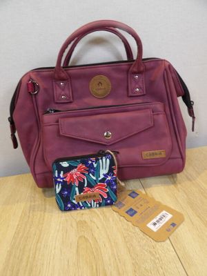 purple handbag and wallet sitting on a wooden table next to a white wall