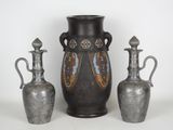 trois vases en argent et deux vases en argent posés sur une surface blanche