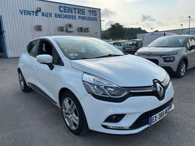 une voiture blanche garée devant un immeuble, à côté d'autres voitures