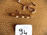a picture of a gold chain and a gold pin on a brown leather surface