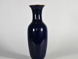 un vase bleu posé sur une surface blanche