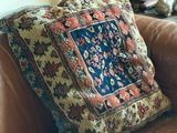 un canapé en cuir marron sur lequel est posé un coussin coloré