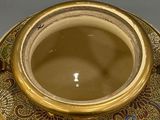 a gold vase with a design on it on a table