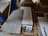 une pile de tôles métalliques posée sur une palette dans un entrepôt